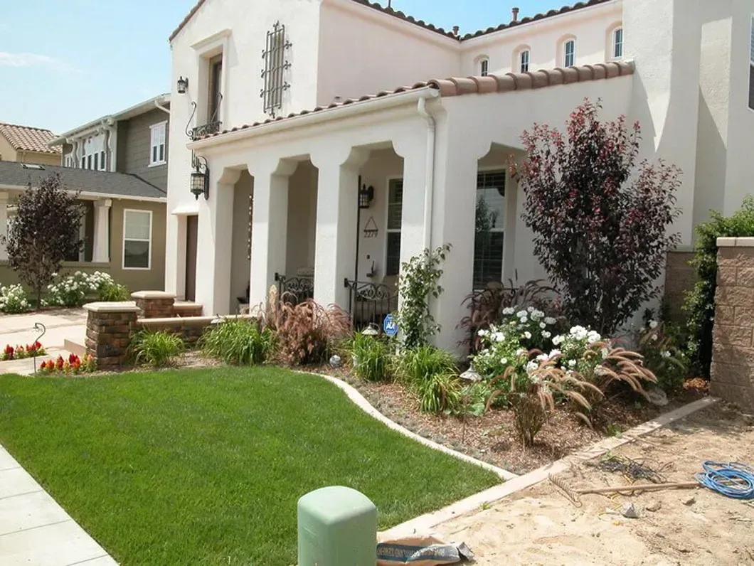 White stucco house with arched porch and landscaped lawn.
