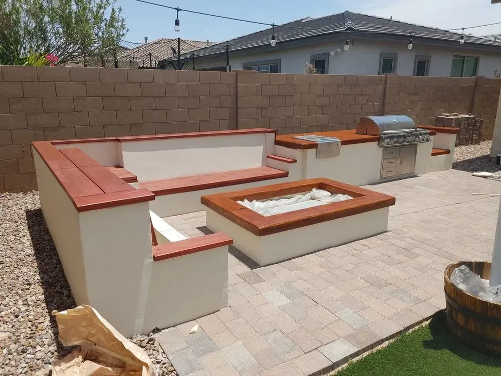 Outdoor patio with built-in seating, fire pit, and grill. Beige stone patio and tan brick wall.