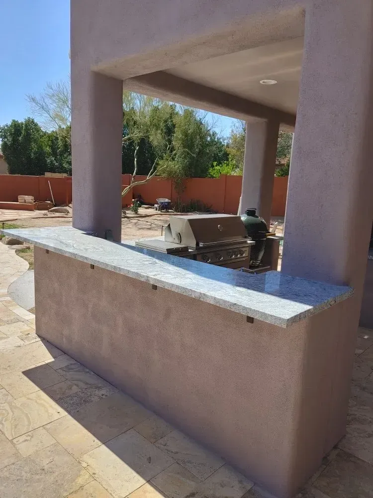 Outdoor kitchen with a granite countertop, grill, and patio.