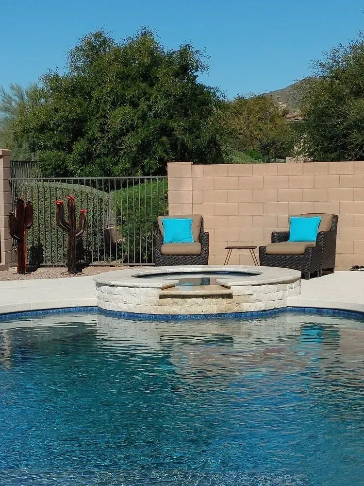 Swimming pool with fire pit, seating, and desert landscape under a clear blue sky.