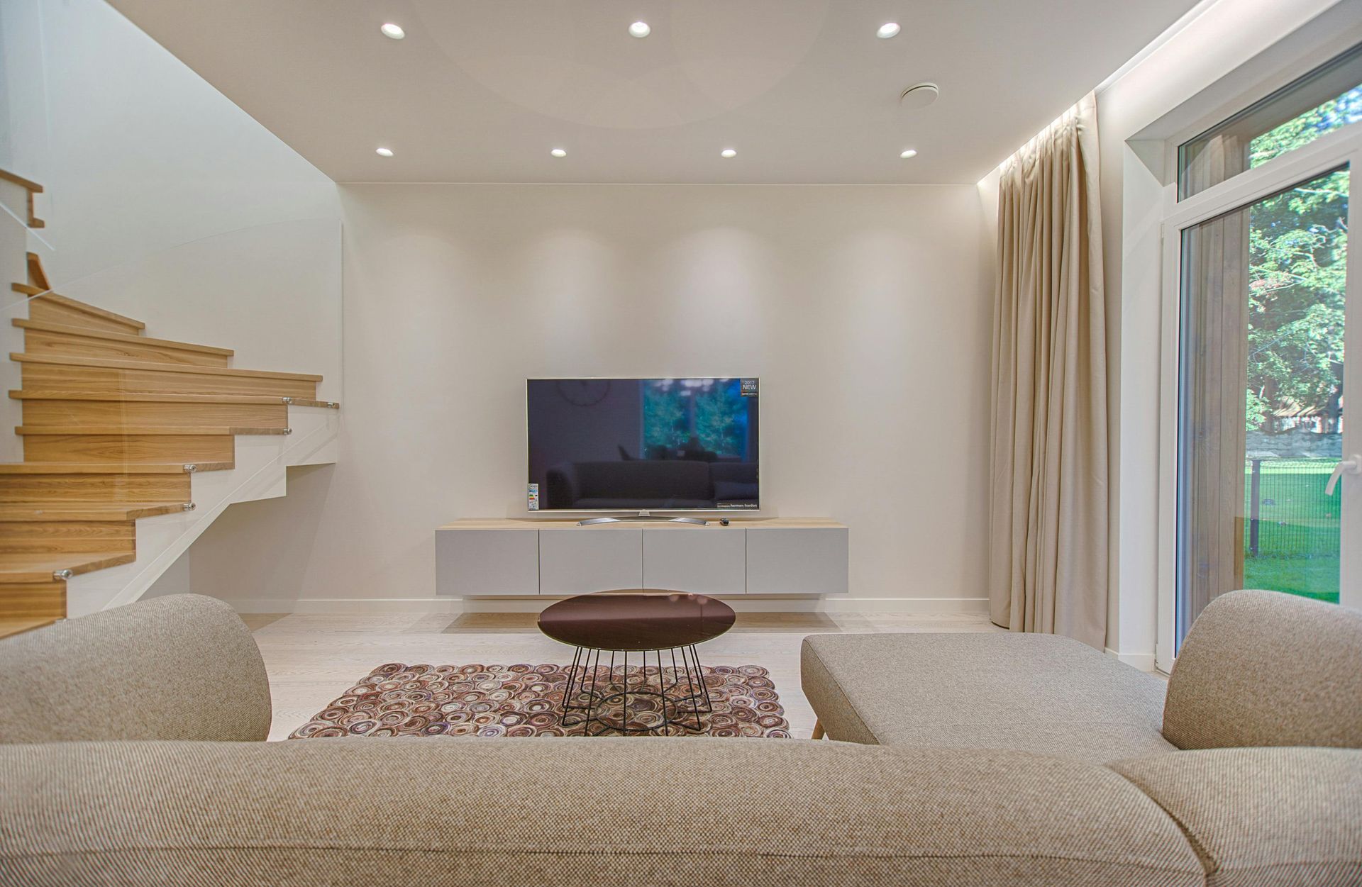 A living room with a couch , television , and stairs.