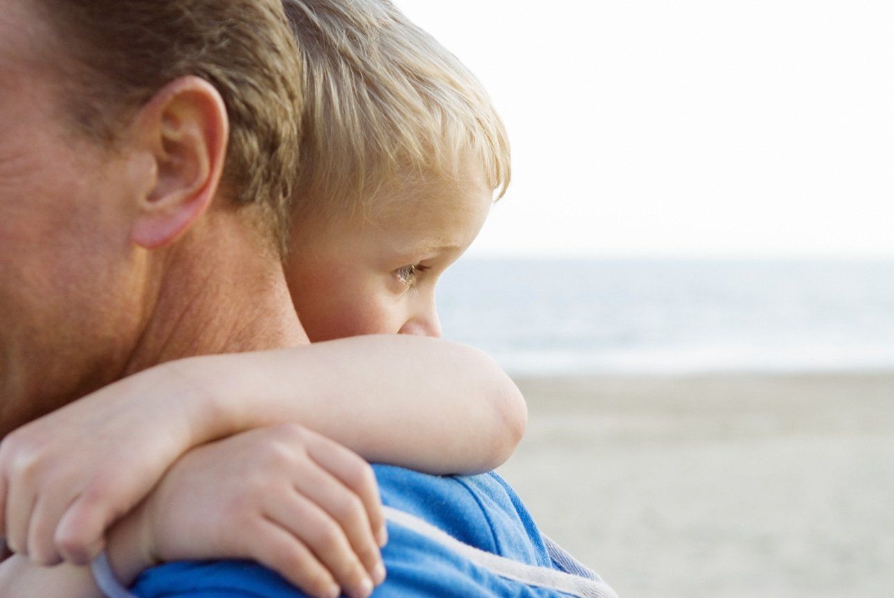 young boy cuddles his father