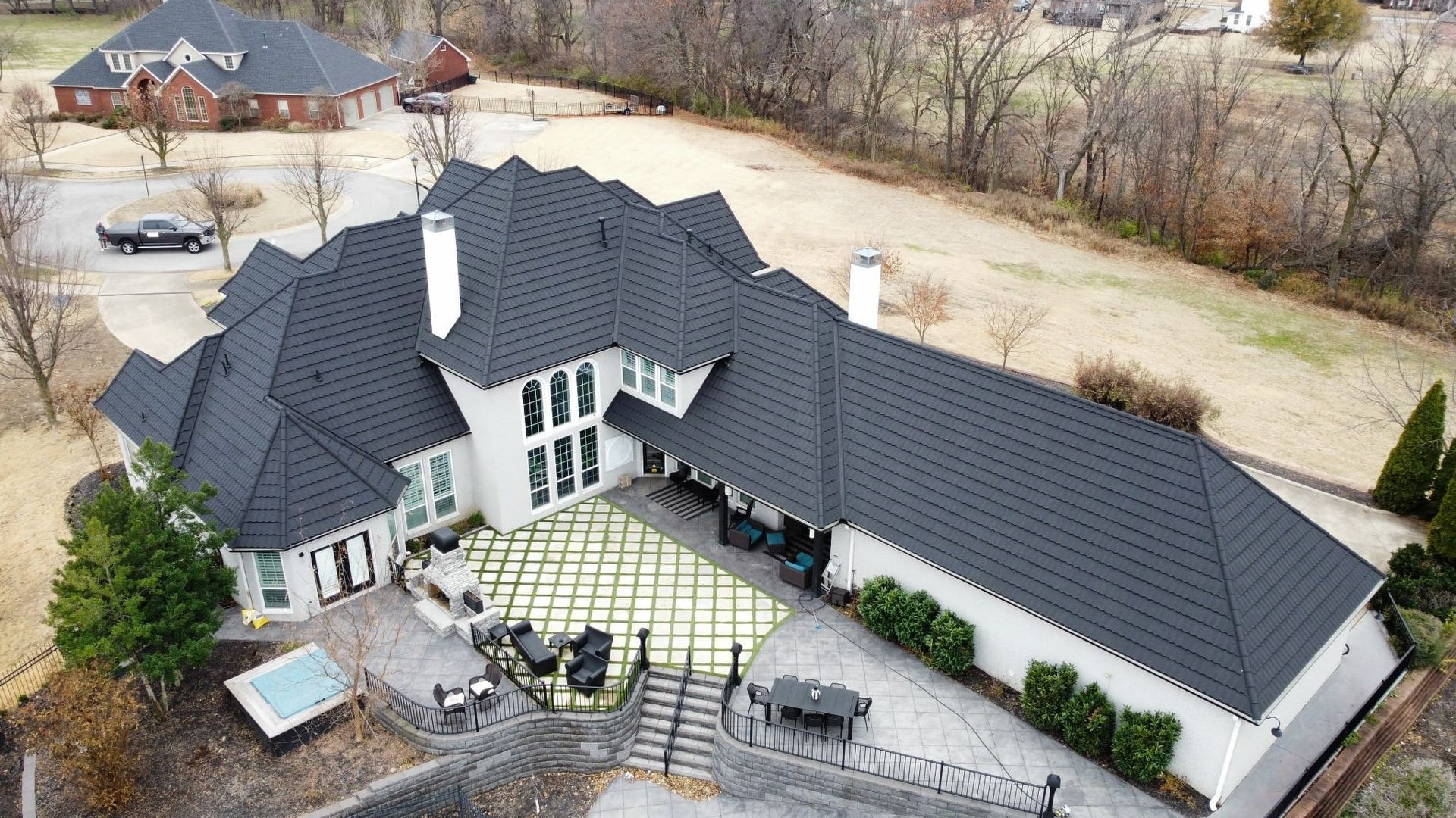 An aerial view of a large white house with a black roof.