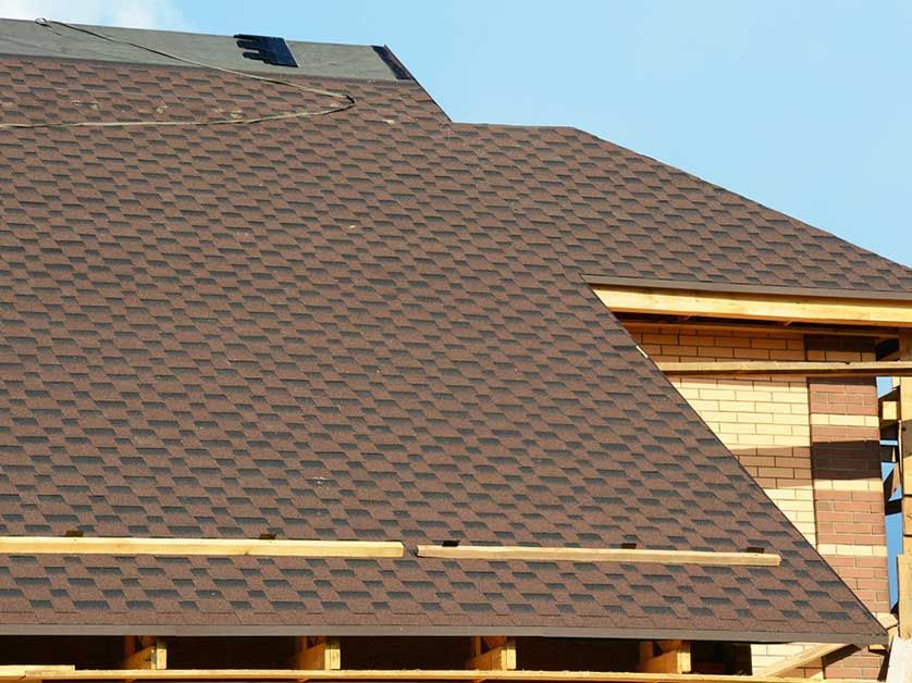 A brown roof is being installed on a brick building.