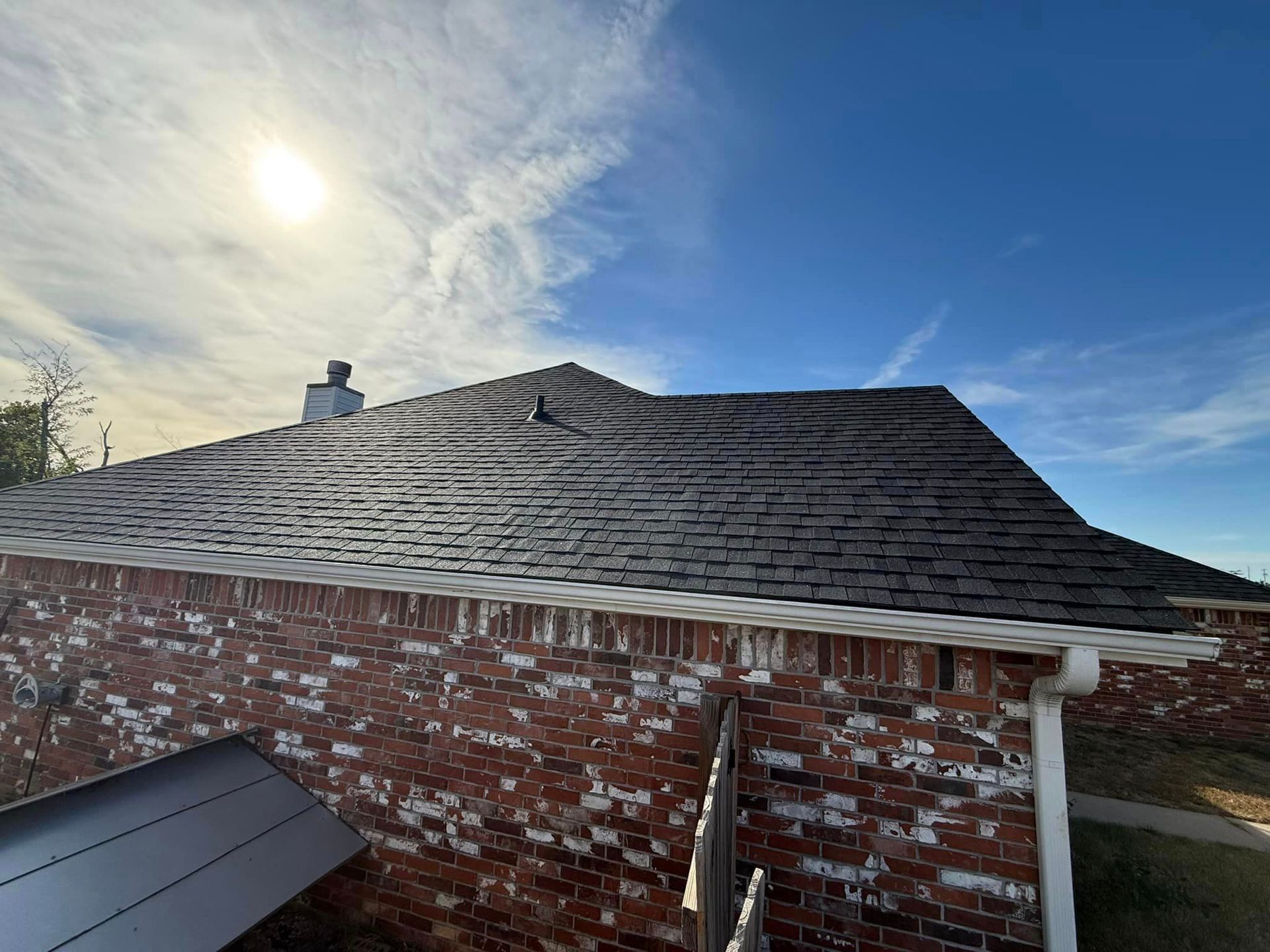 The sun is shining on the roof of a brick house.