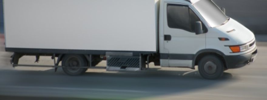 A white box truck driving on a paved road.