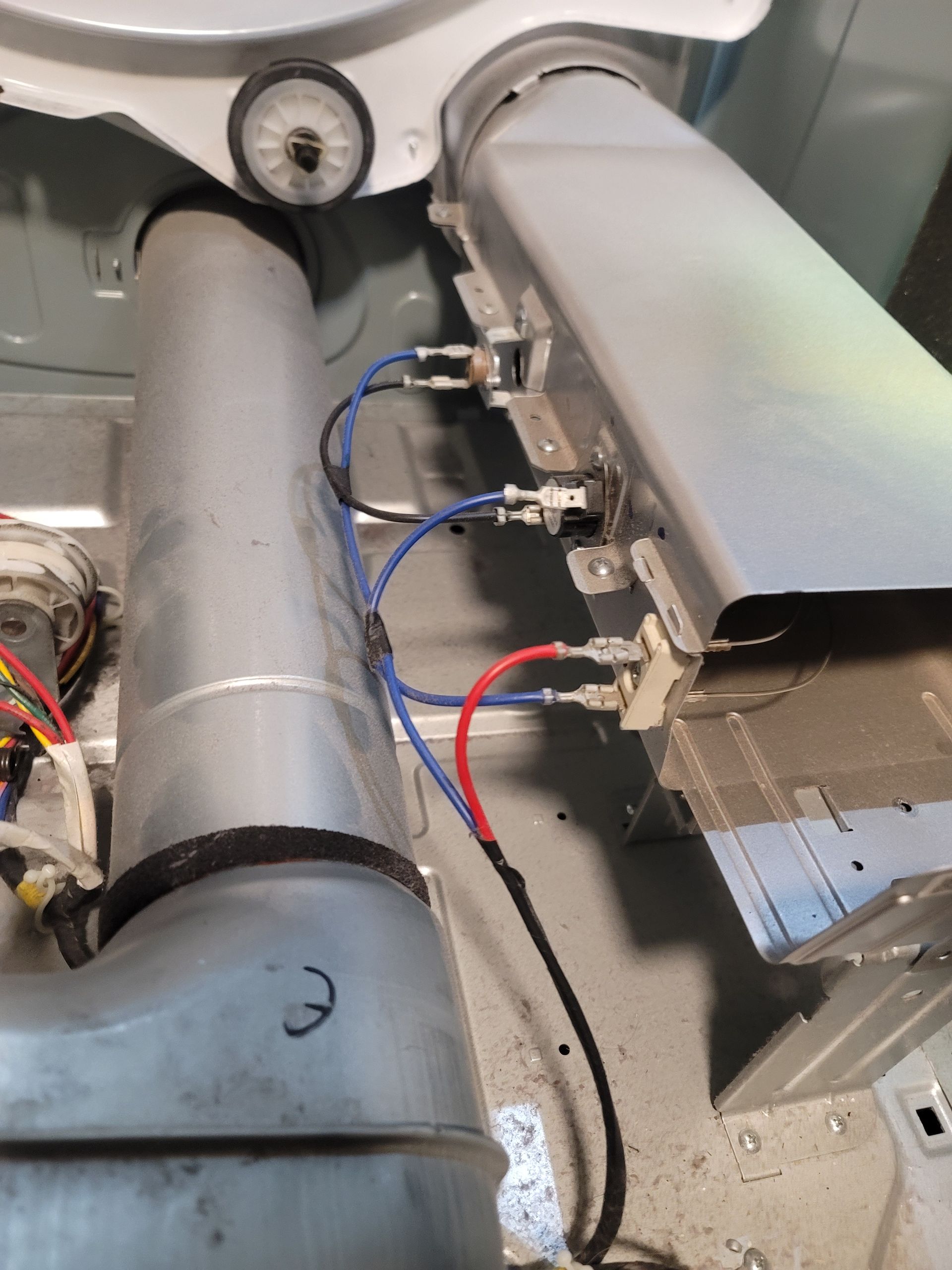 Interior view of a dryer showing the heating element, vent, and electrical wiring in a metallic setting.