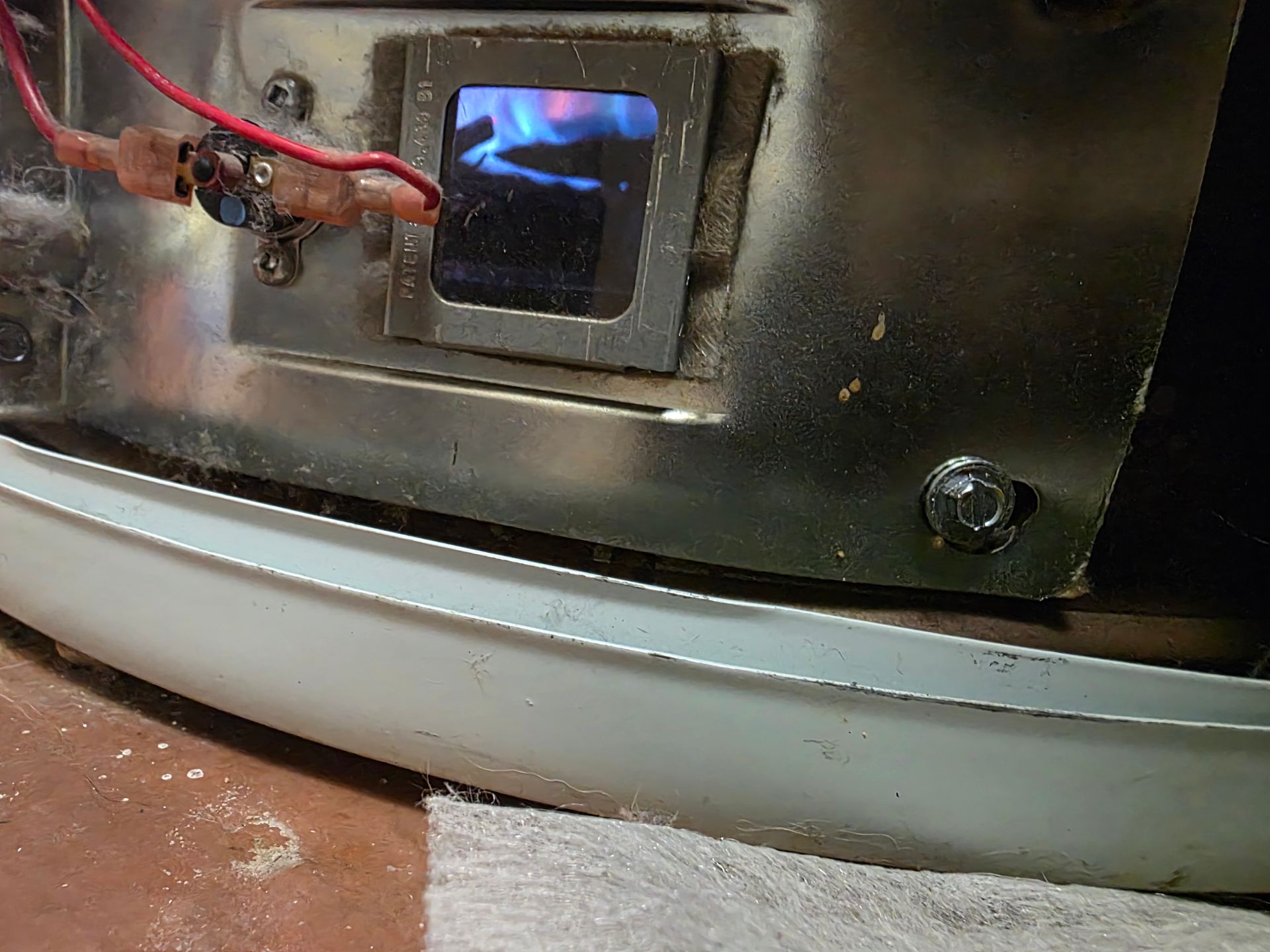 Close-up of a water heater with a blue flame visible through a small window.