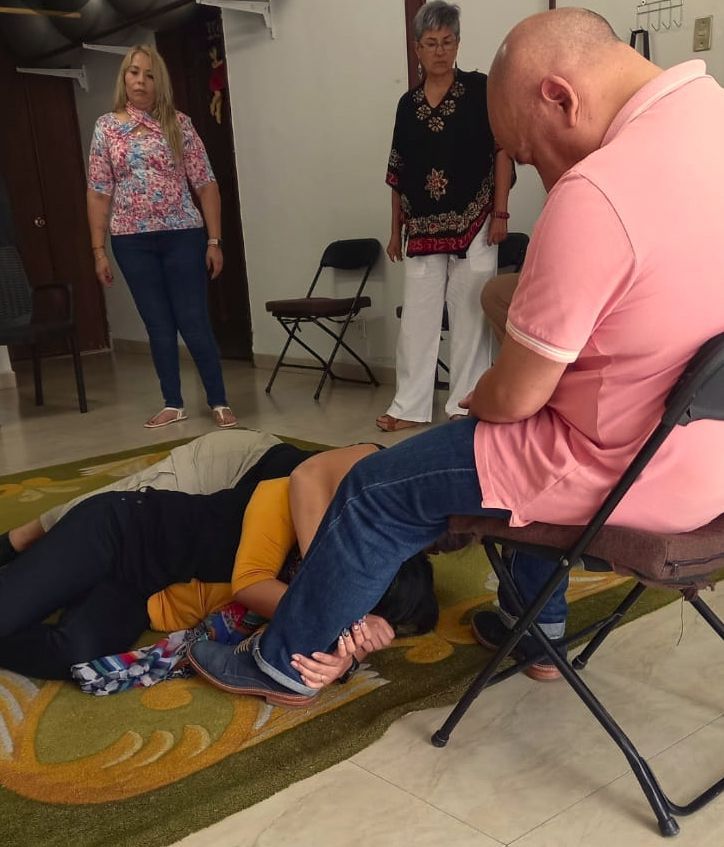 Tres personas tumbadas en el suelo, supervisadas por dos individuos de pie y uno sentado.