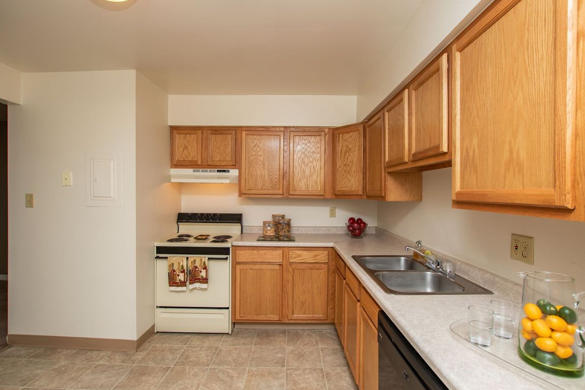 Kitchen with light brown cabinets, white appliances, and a gray countertop.