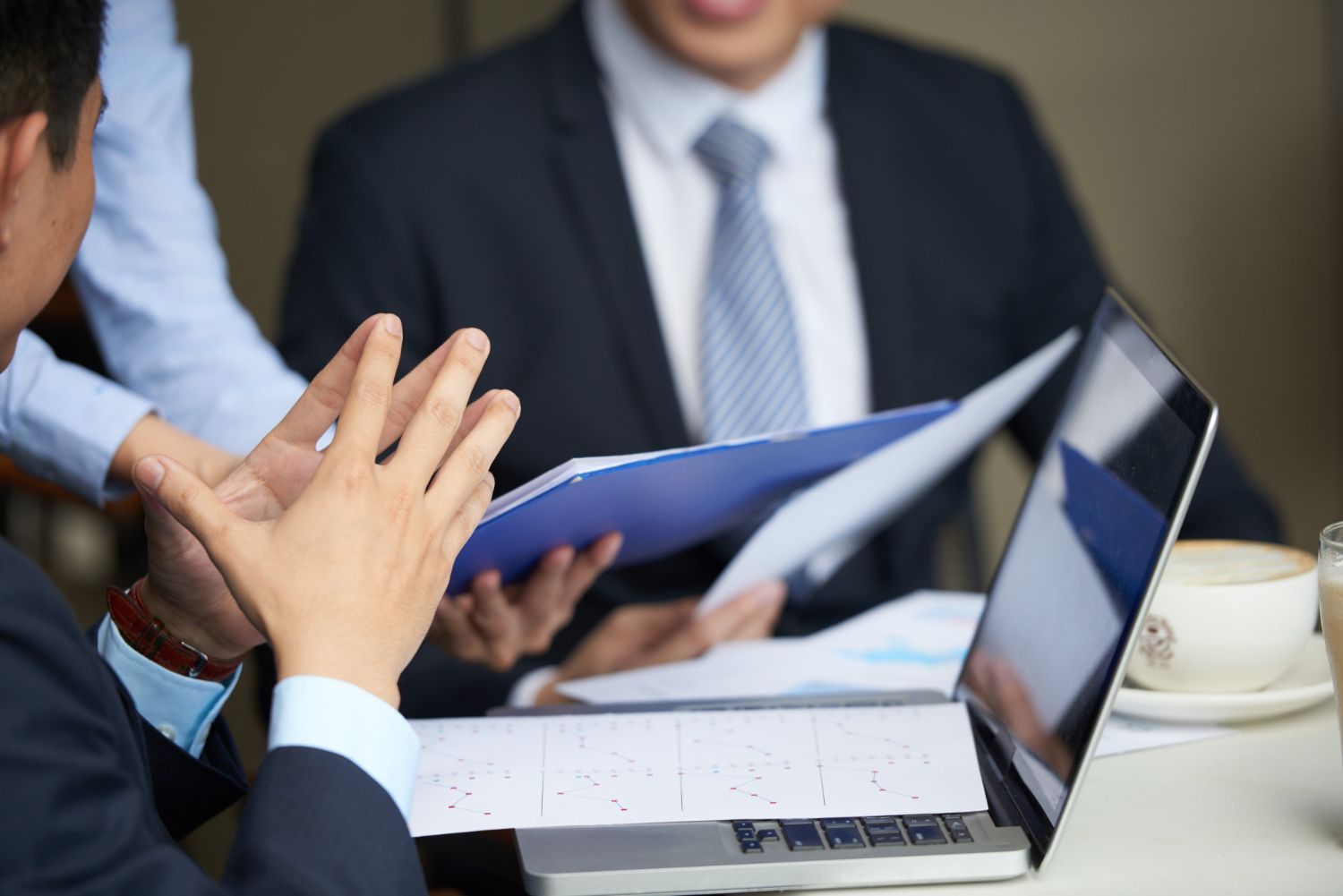 Two business professionals in suits reviewing documents, discussing strategy.