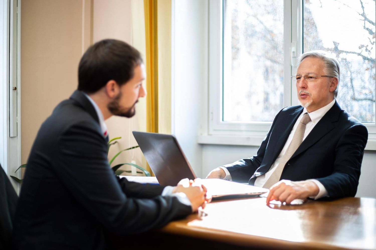 Two business professionals in suits reviewing documents, discussing strategy.