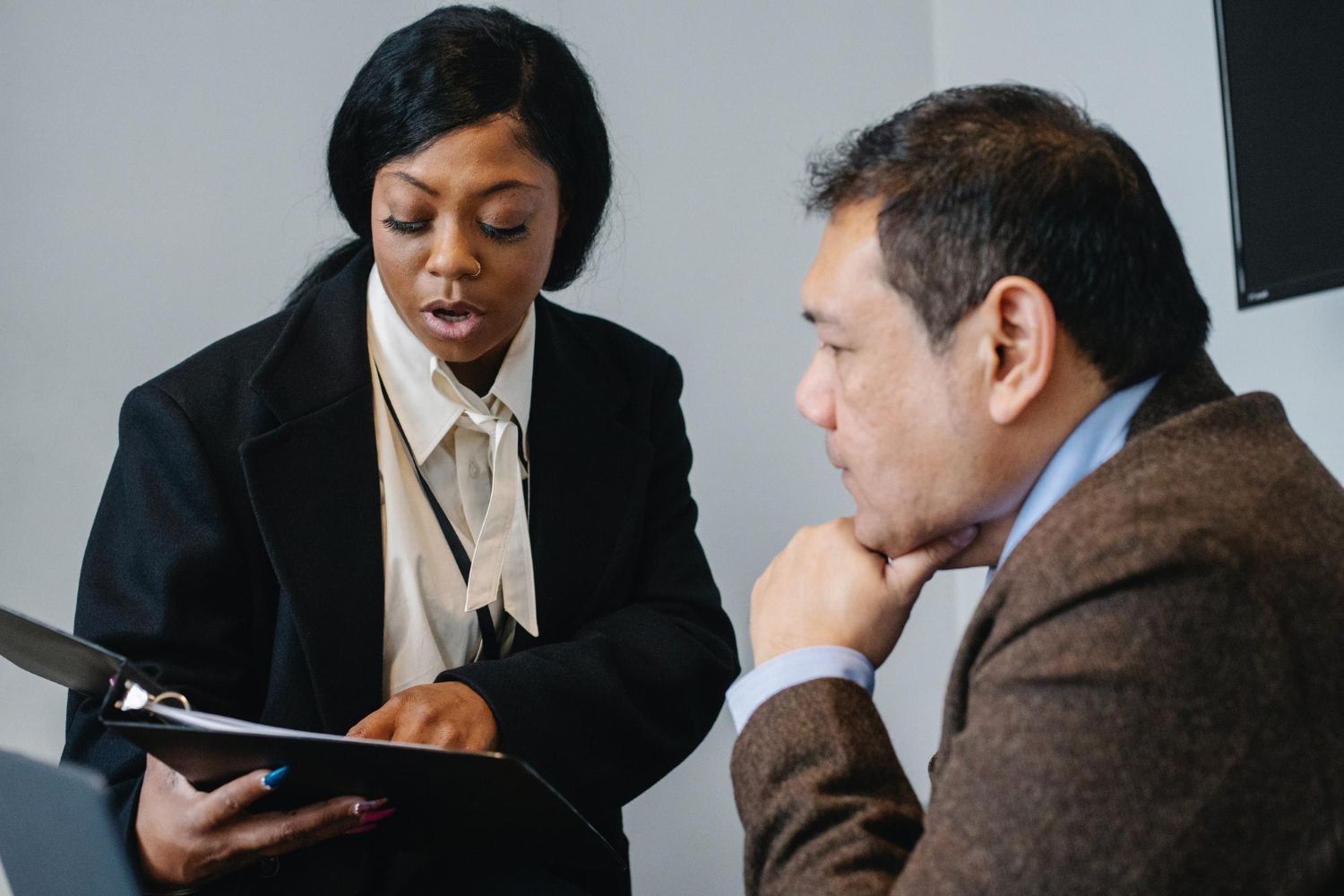 Two business professionals in suits reviewing documents, discussing strategy.