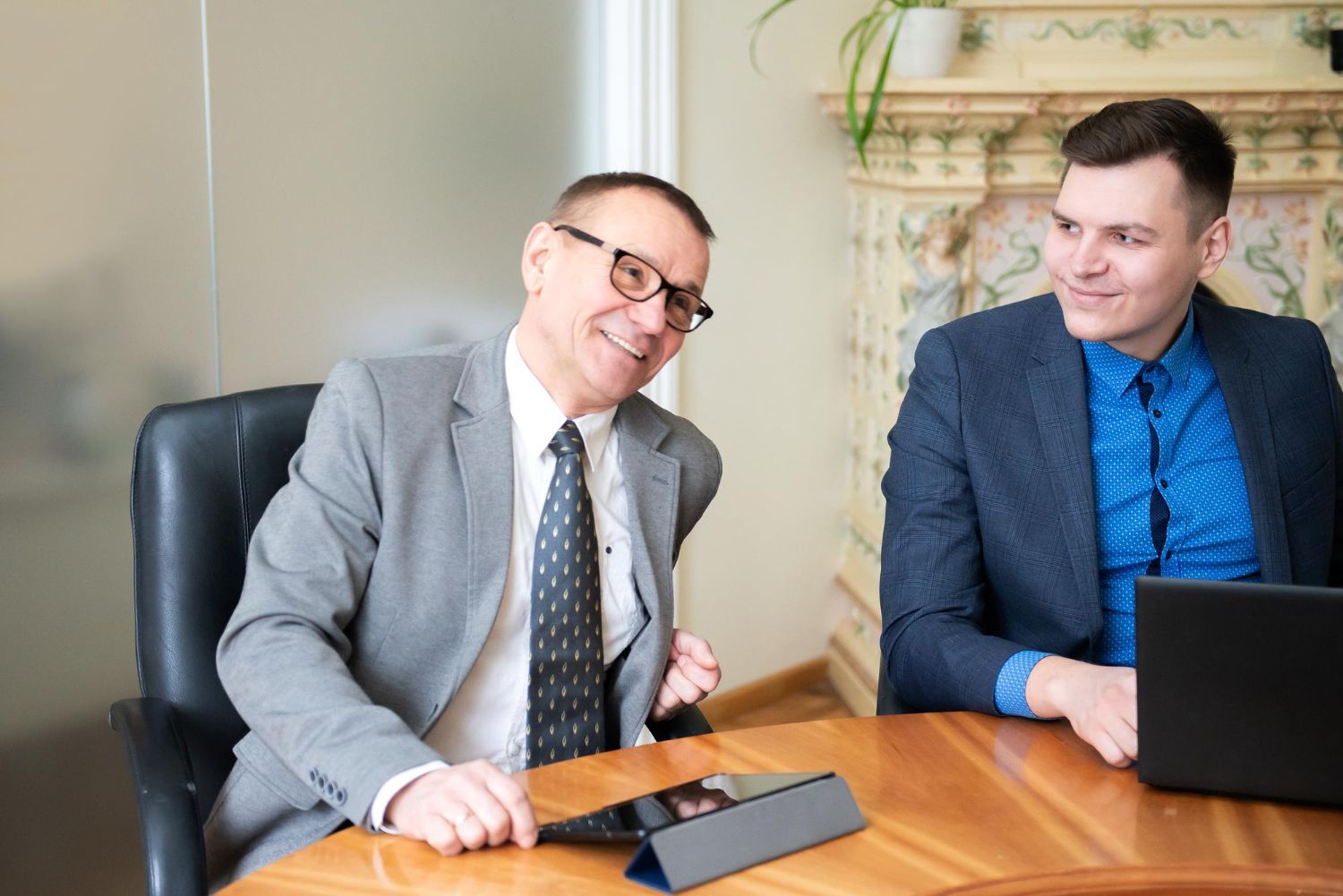 Two business professionals in suits reviewing documents, discussing strategy.