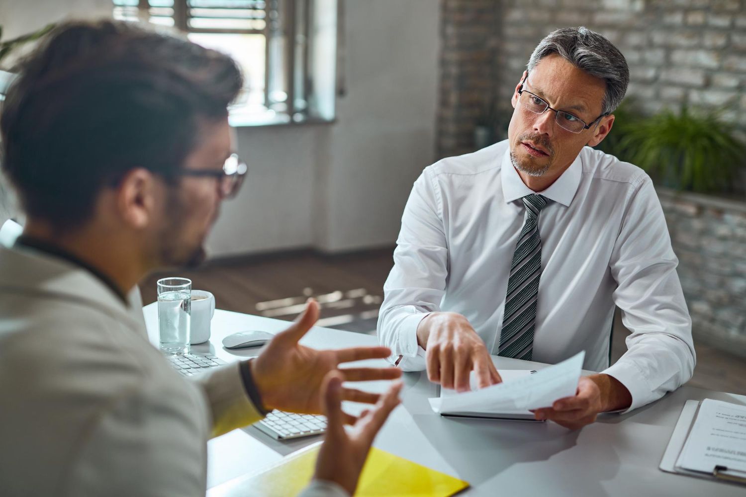 Two business professionals in suits reviewing documents, discussing strategy.