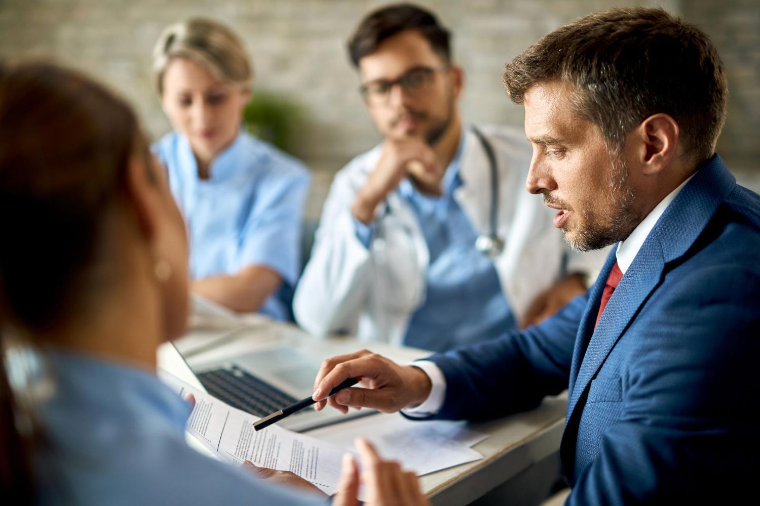 Two business professionals in suits reviewing documents, discussing strategy.