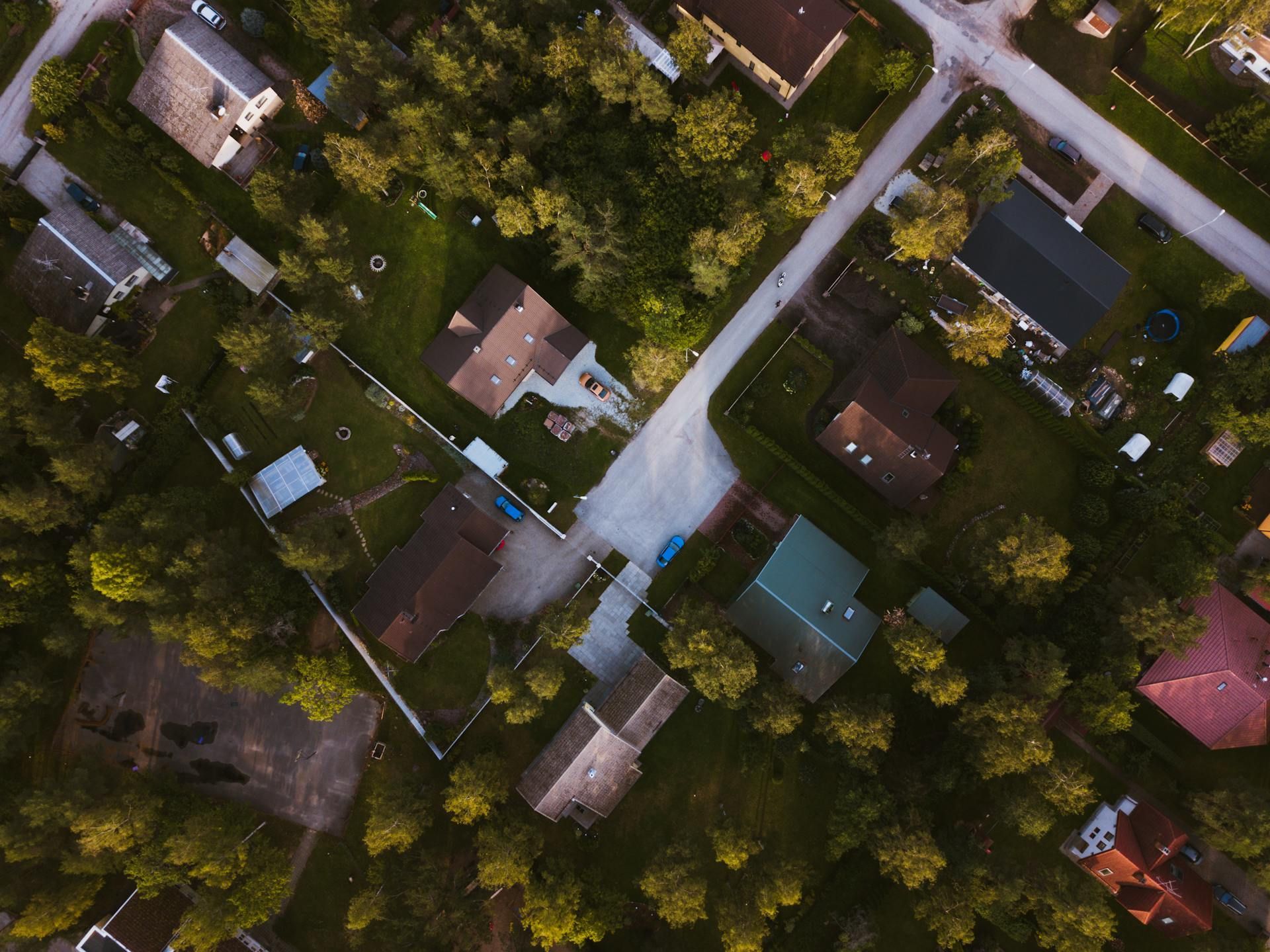 Aerial view of houses and roads surrounded by trees.