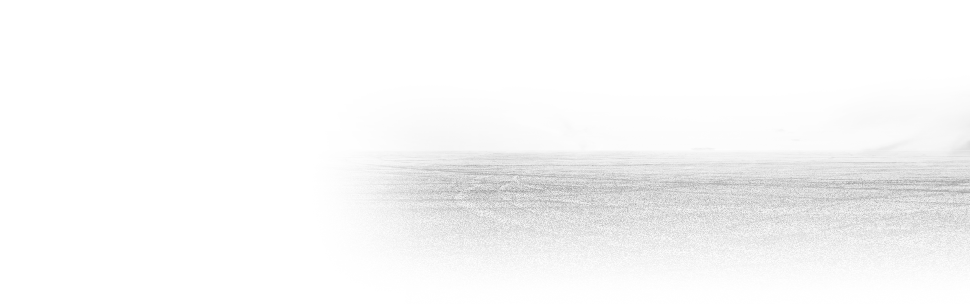 A faint, blurry view of a textured, light-colored landscape, possibly a sandy surface or distant horizon, in monochrome.