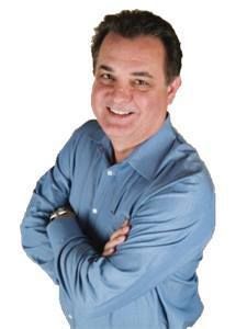 A woman is sitting at a desk with a laptop and a vase of flowers.