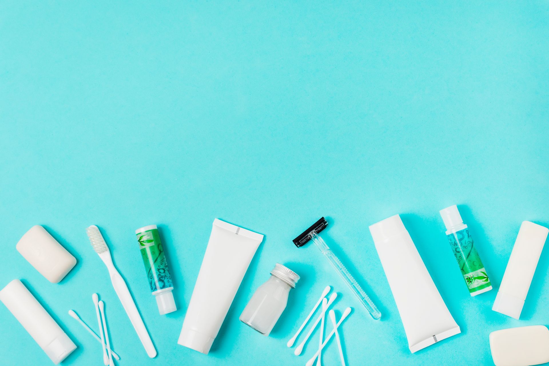 Artículos de aseo dispuestos sobre un fondo azul: jabón, cepillo de dientes, pasta de dientes, hisopos de algodón