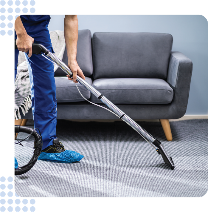 A man is using a vacuum cleaner to clean a carpet in a living room.