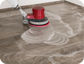 A person is cleaning a wooden floor with a machine.