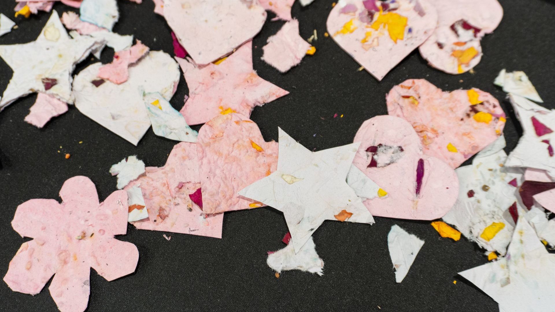 A pile of pink and white hearts and stars on a black surface.