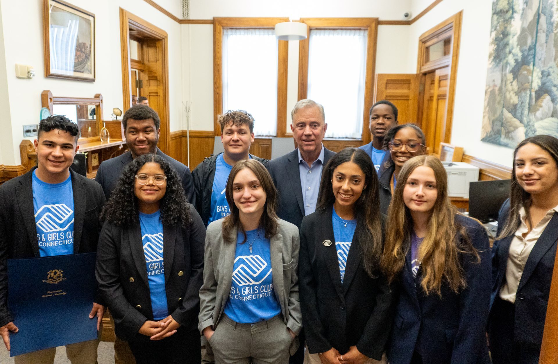 A group of young people are posing for a picture with a man in a suit.