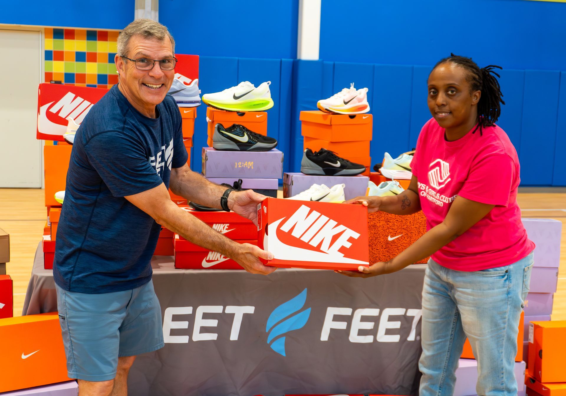 A man and a woman are standing in front of a pile of nike shoes.
