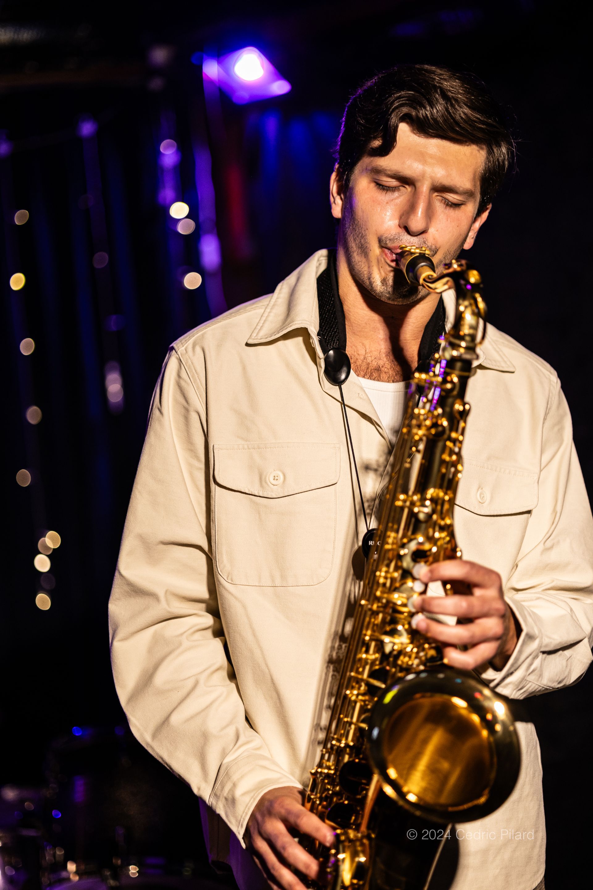 Matthew Pearl is playing a saxophone in a dark room.