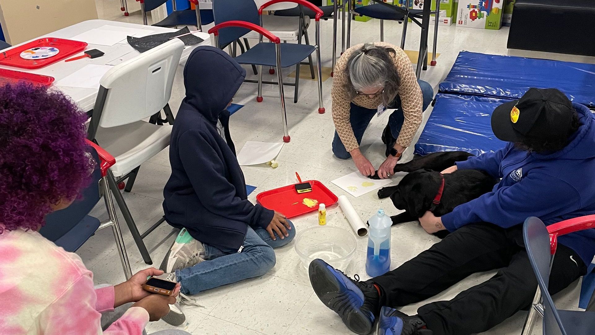 A group of people are sitting on the floor with a dog.