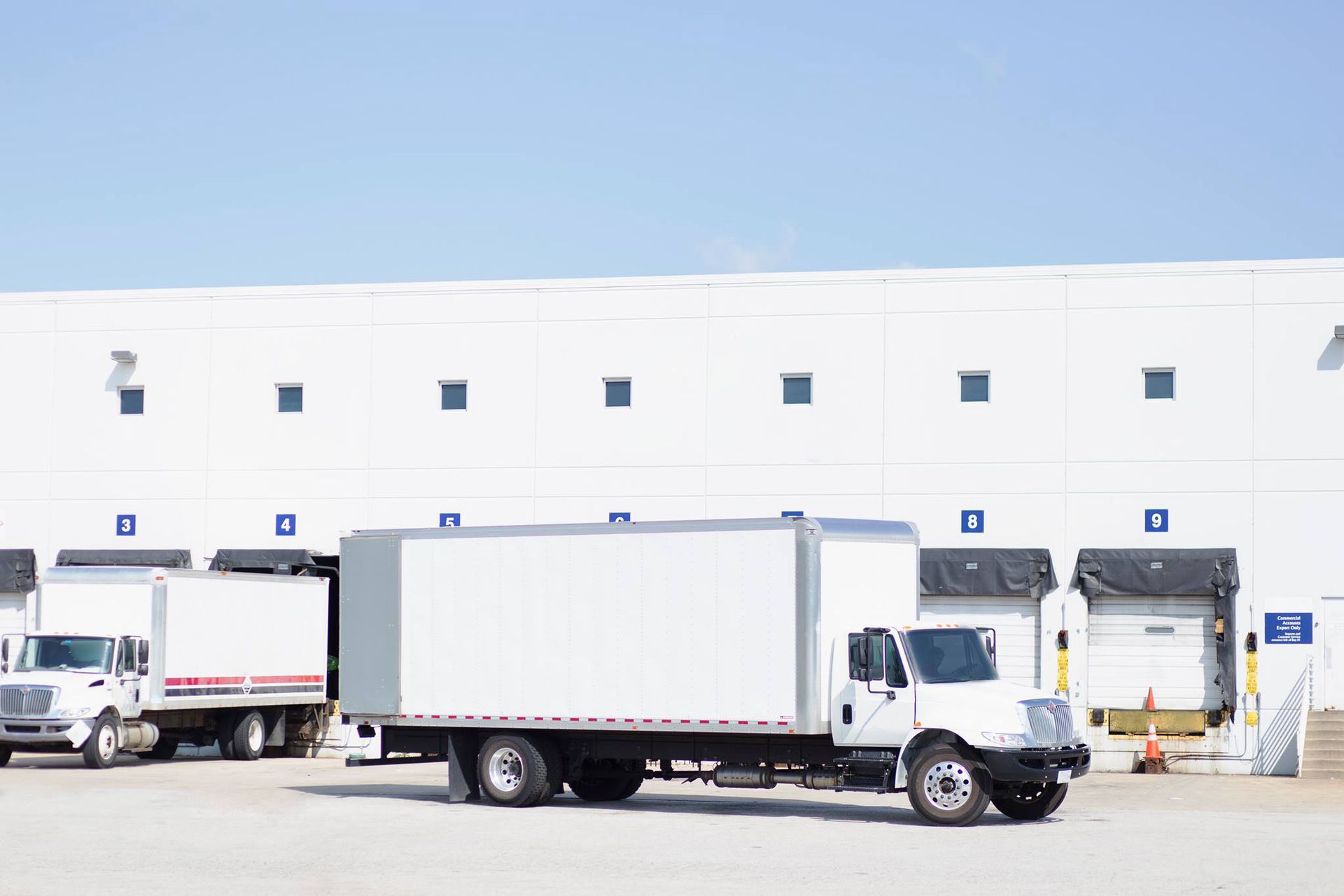 A row of trucks are parked in front of a warehouse.
