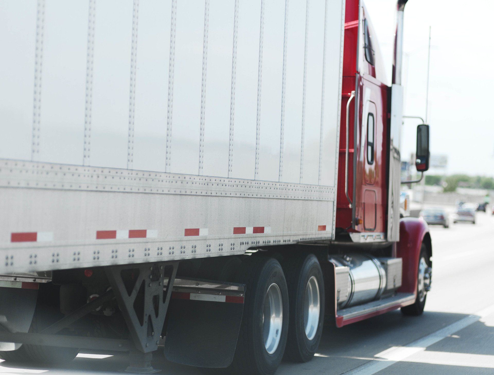 A red and white semi truck is driving down a highway.