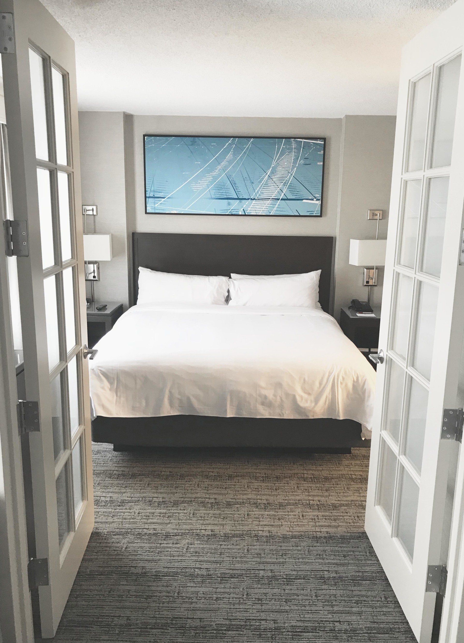 A hotel room with a large bed and a painting on the wall