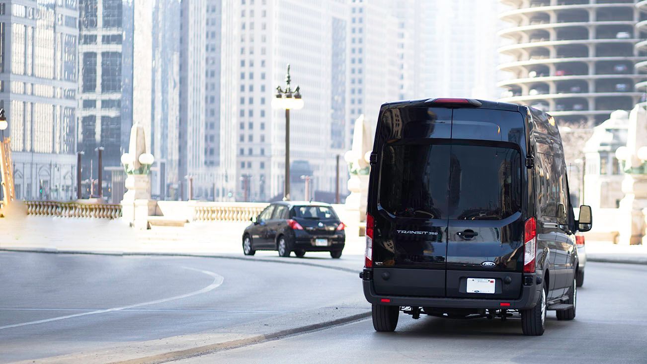 A black van with the word trip on the back is driving down a city street.