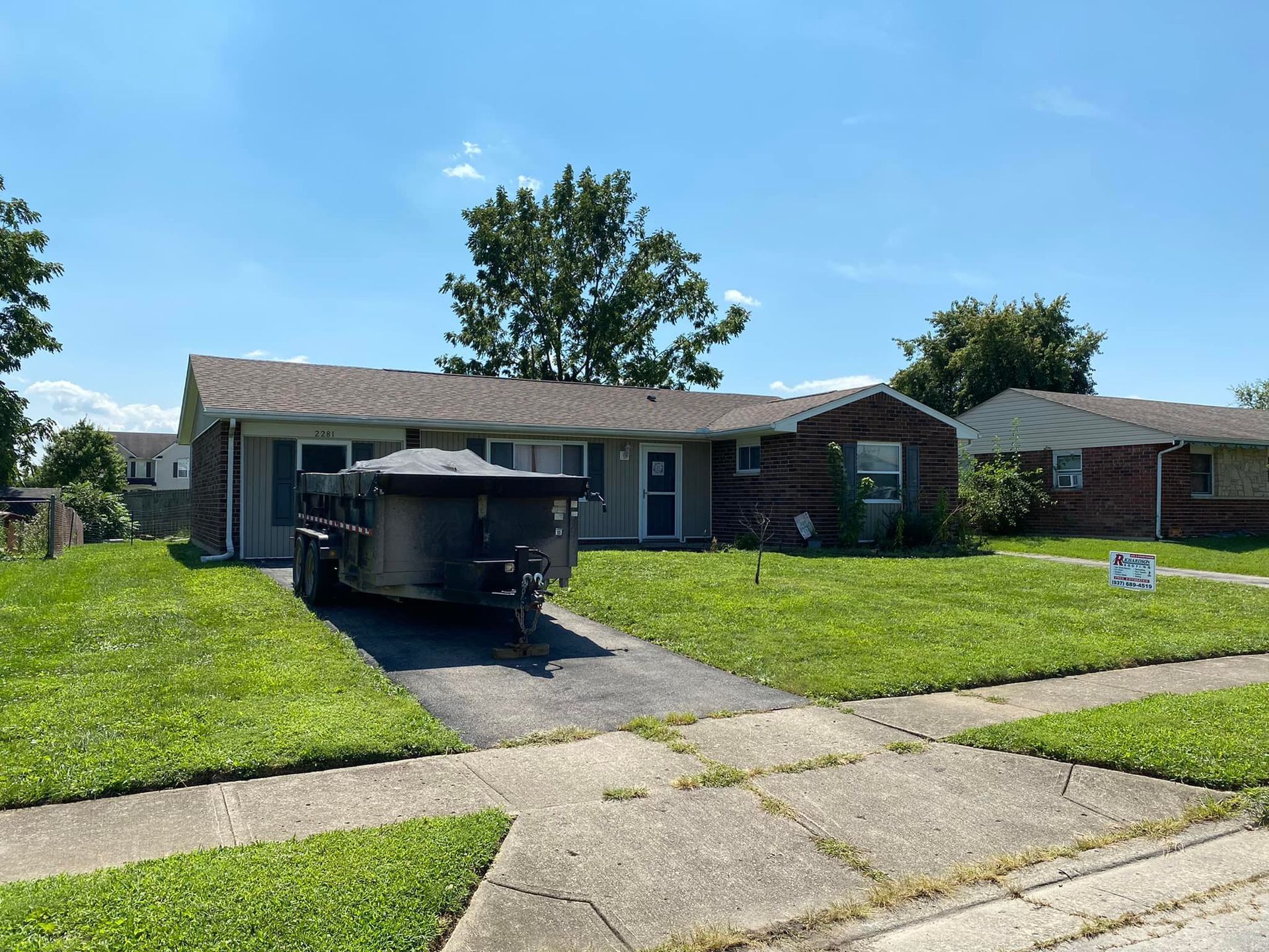 A trailer is parked in front of a brick house.