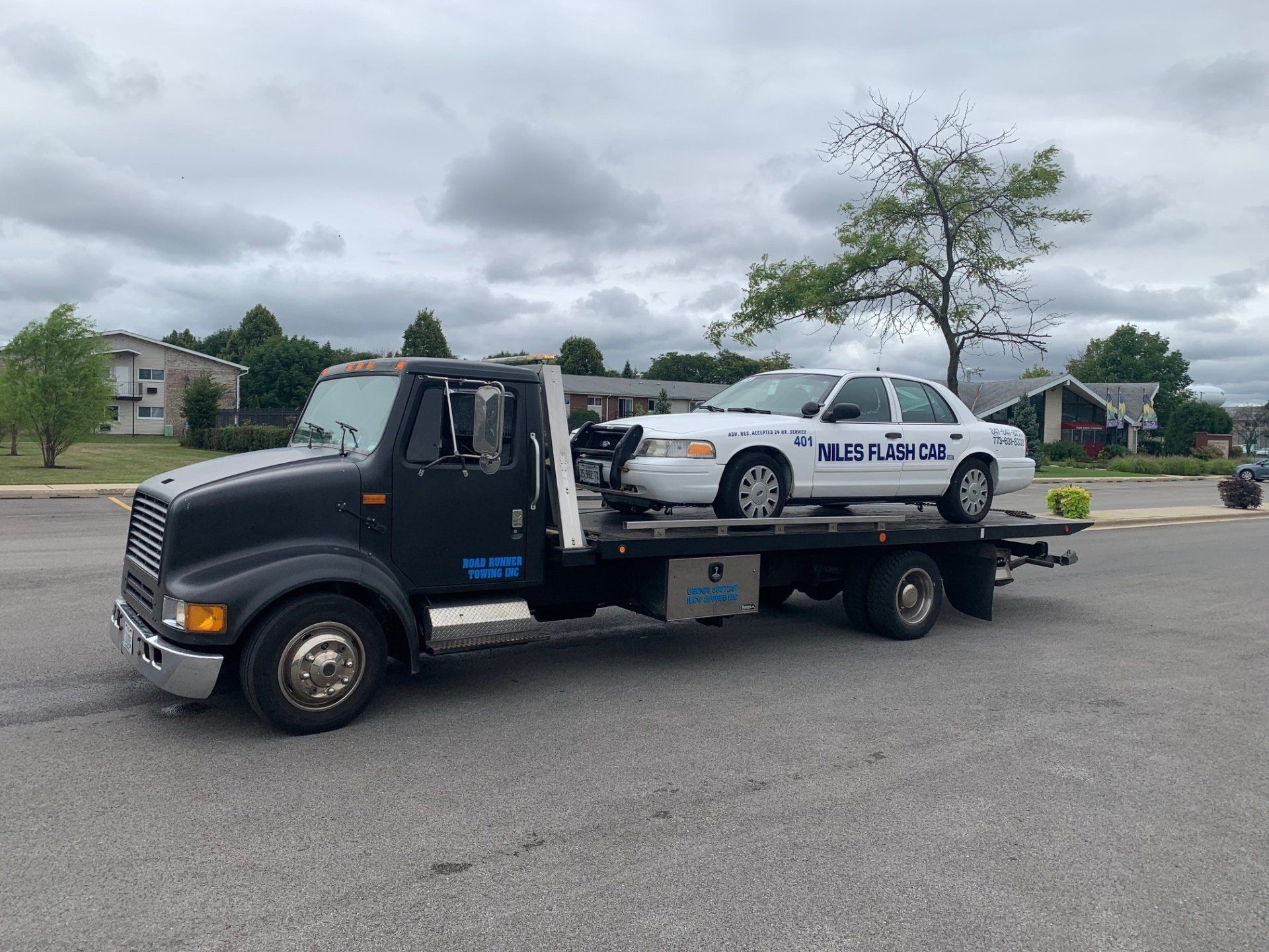 A tow truck with a police car on the back of it.