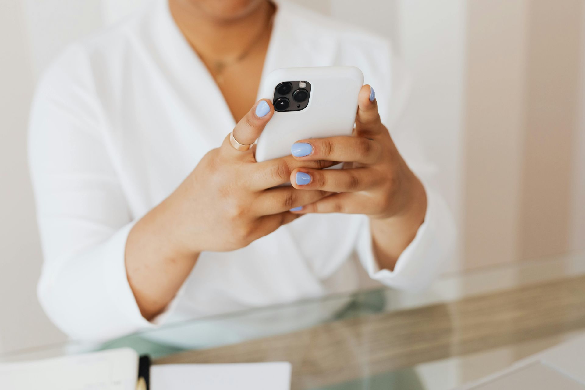 A woman is sitting at a table using a mobile phone.