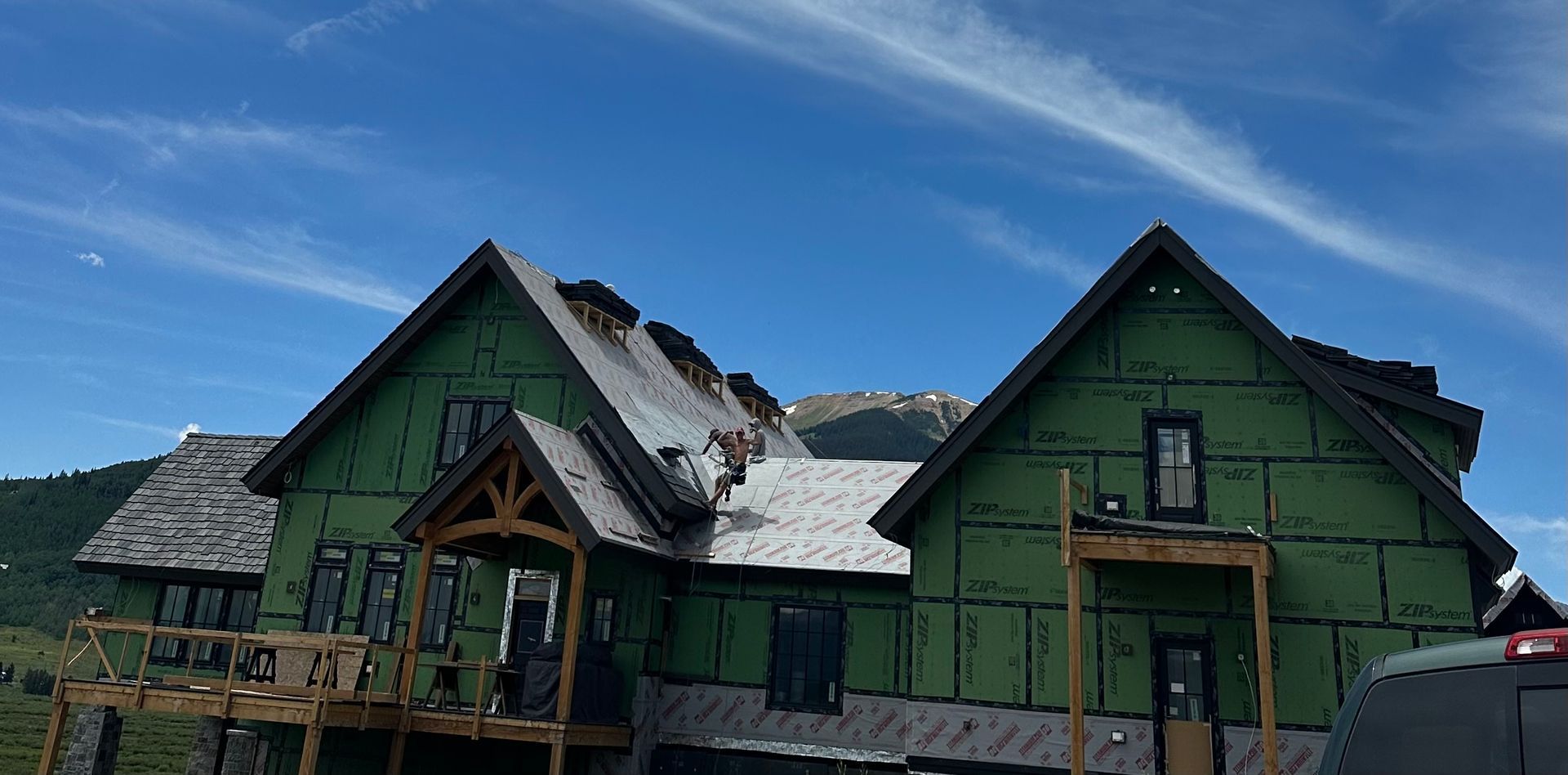 A large house is being built with a mountain in the background.
