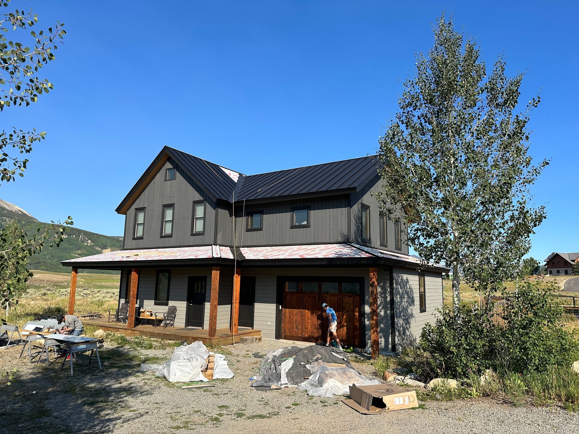 A man is standing in front of a large house with a black roof.