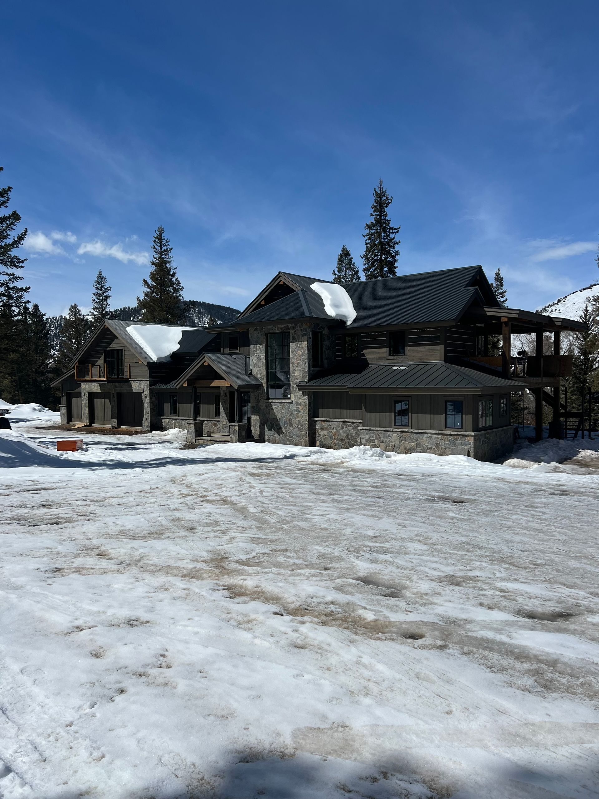 A large house is surrounded by snow and trees