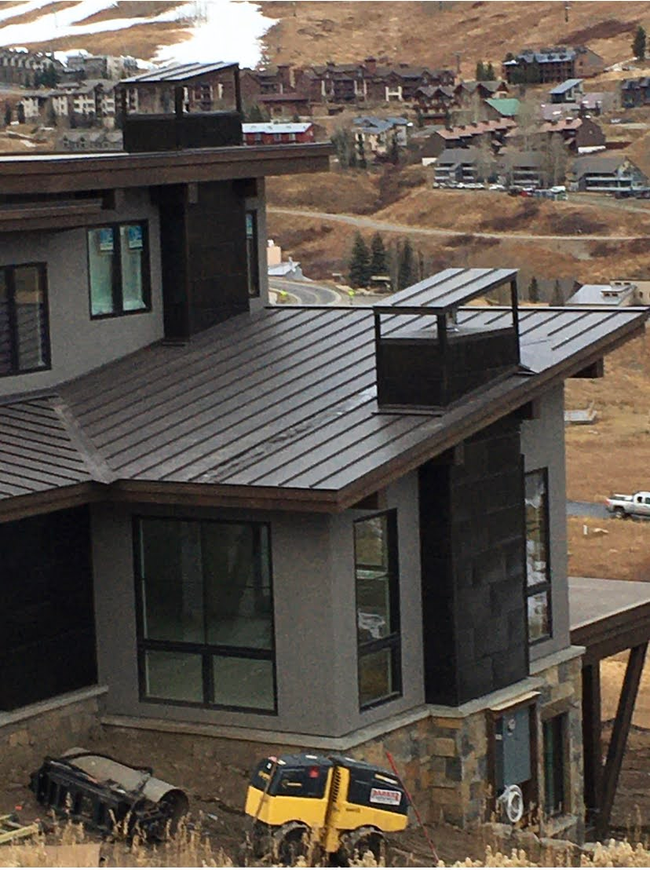 A large house with a metal roof is sitting on top of a hill.