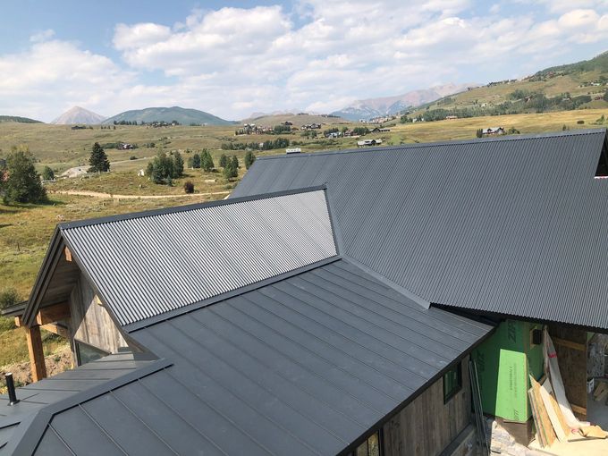 An aerial view of a house with a gray roof and mountains in the background.