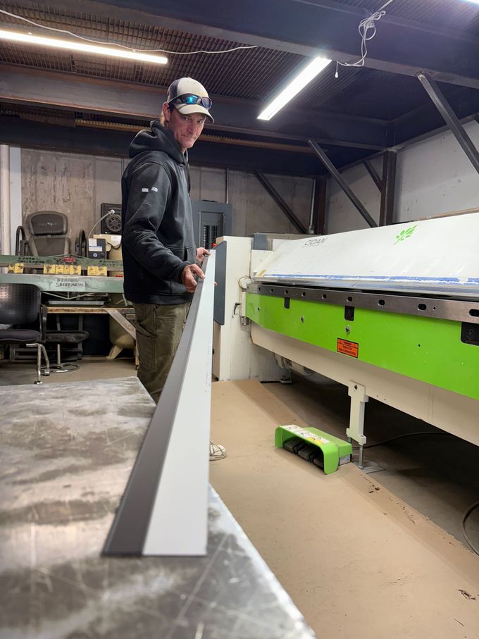 A man is standing next to a green machine in a factory.
