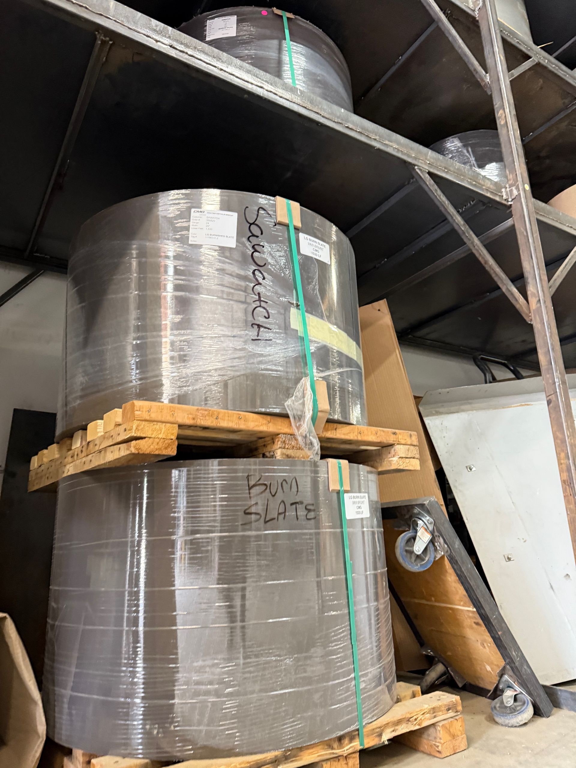 Two rolls of paper are stacked on top of each other on wooden pallets.