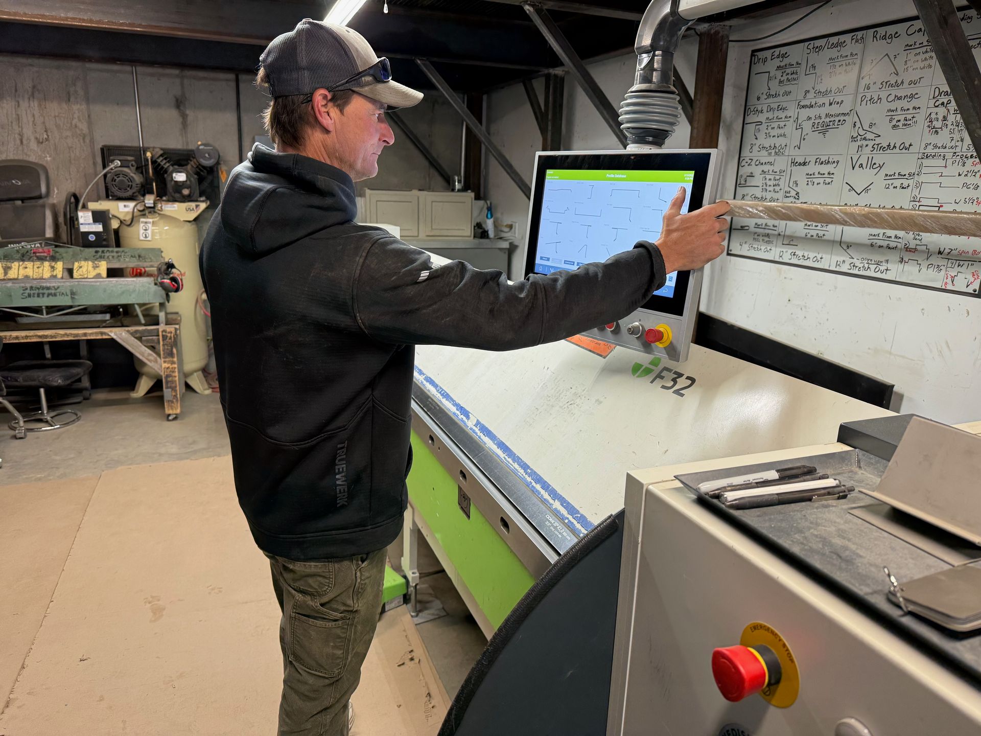 A man is standing in front of a computer in a factory.