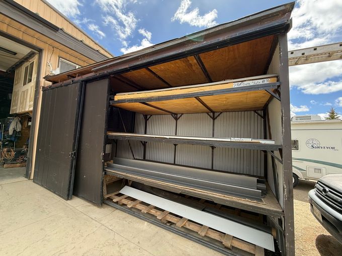 A shed with a lot of shelves and a truck parked in front of it.