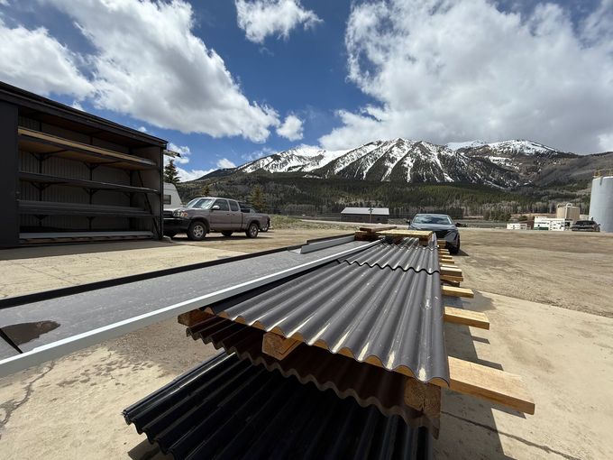A truck is parked in front of a pile of corrugated metal