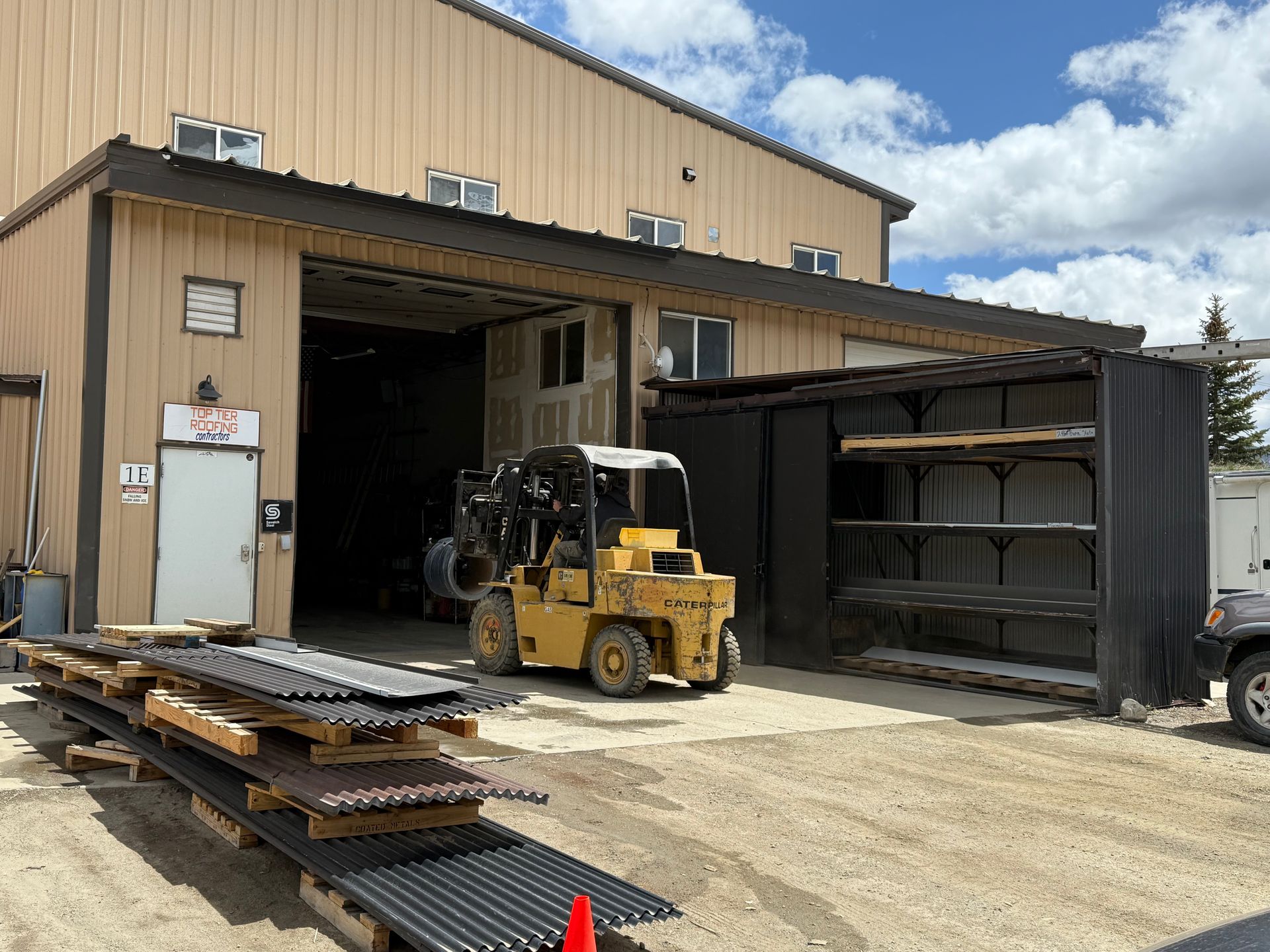 A yellow forklift is parked in front of a large building.