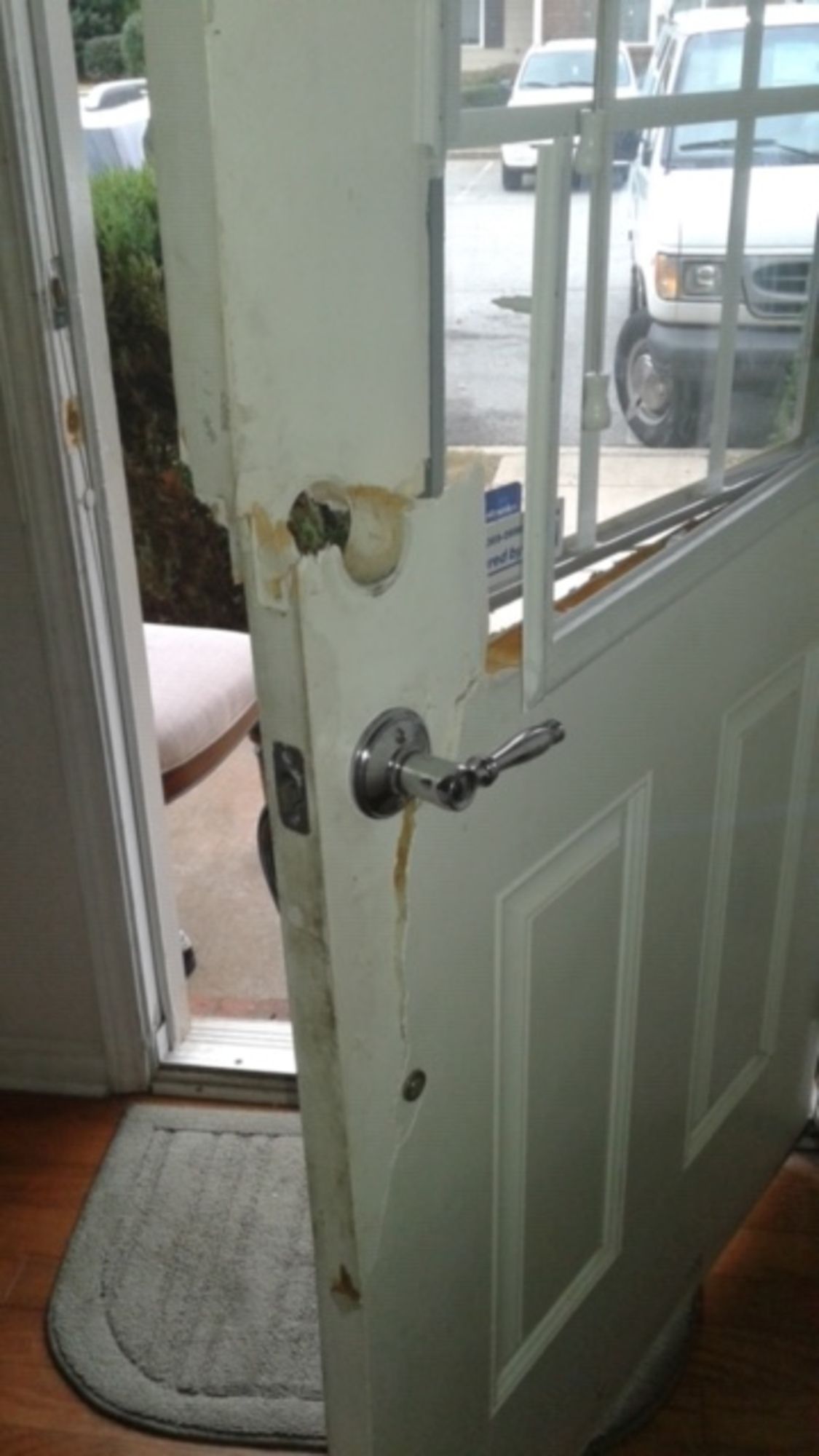 A white door with a broken handle is open to a doorway.